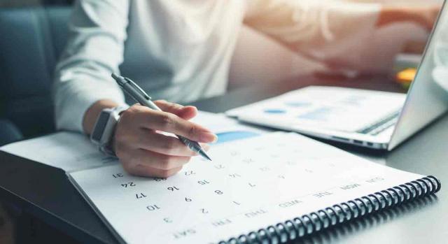 Ejercicio. Mujer con un portatil y señalando con un bolígrafo un día en un calendario