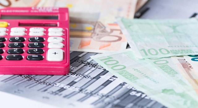 Cuestiones relacionadas con el cobro de dividendos desde el punto de vista del socio. Imagen de una calculadora rosa sobre unos billetes de 100 euros
