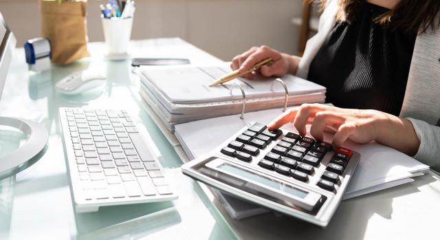 Compras exntas de IVA y compras no sujetas a IVA. Imagen de una mujer haciendo cuentas con la calculadora y un ordenador