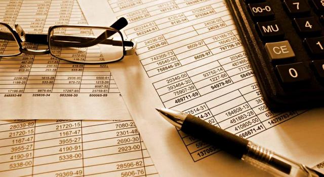 Instrucción de contabilidad. Imagen de unas gafas, un bolígrado y una calculadora encima de documentos financieros