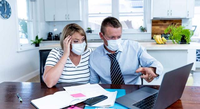 Necesidades financieras derivadas del COVID-19. Hombre y mujer con mascarilla mirando la pantalla de un ordenador