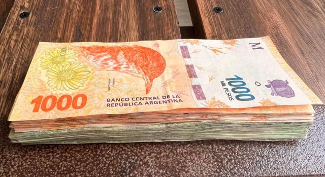 El impacto de la devaluación del peso argentino en empresas españolas. Imagen de un montoncitos de billetes de 1000 pesos