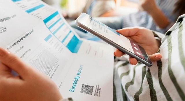 La factura electrónica. Imagen de persona con factura y móvil en las manos
