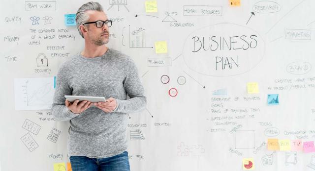 Hombre emprendedor con tablet y pizarra creando un business plan