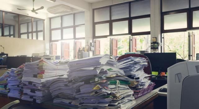 Todo lo que necesitas saber sobre la legalización de los libros contables. Imagen de una oficina con las mesas llenas de montañas de papeles