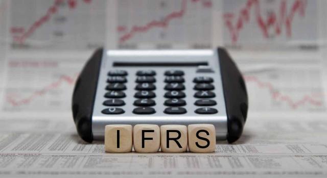 Una calculadora y unos dados con las letras IFRS  (NIIF)