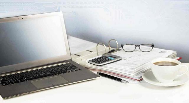 Digitalización. Portátil, papeles, gafas, taza de café sobre una mesa