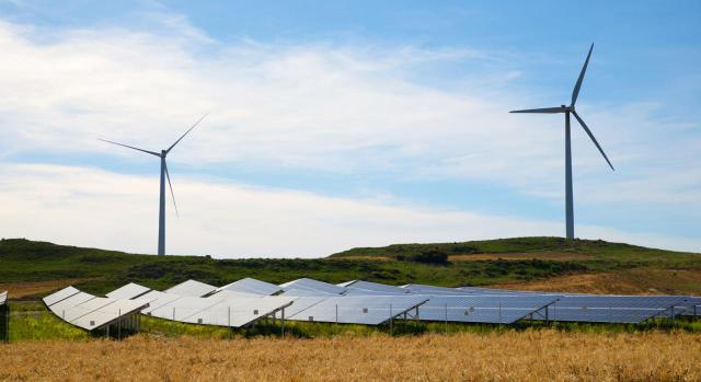 Modificaciones clave en las NIIF 9 y 7 sobre contratos de electricidad. Imagen de un campo con placas solares y molinos
